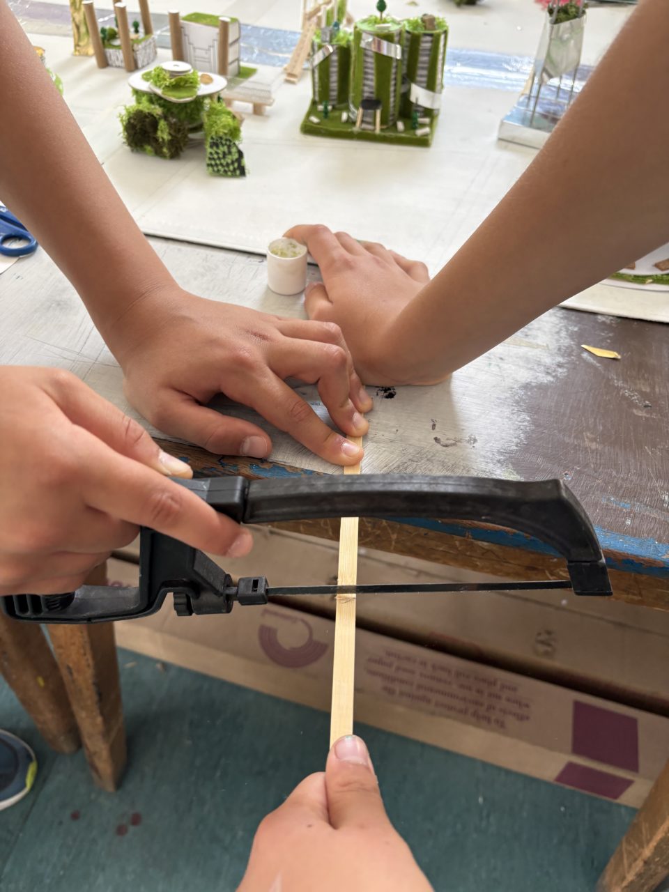 Children measuring ans sawing a frame for the base board.